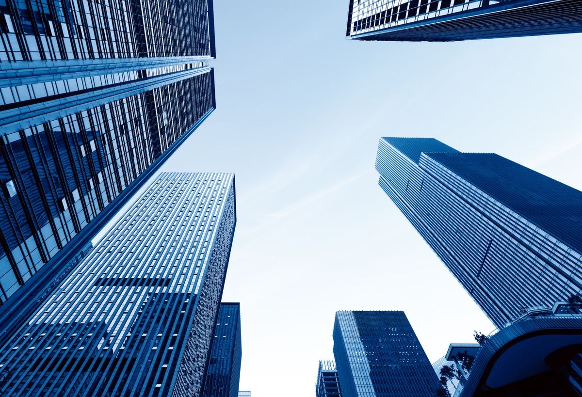 Bottom view of modern skyscrapers in business district against blue sky Bottom view of modern skyscrapers in business district against blue sky